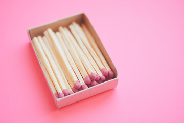 Matches in open paper box on a pale pink table.