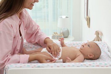 Mother changing her baby's diaper on table at home