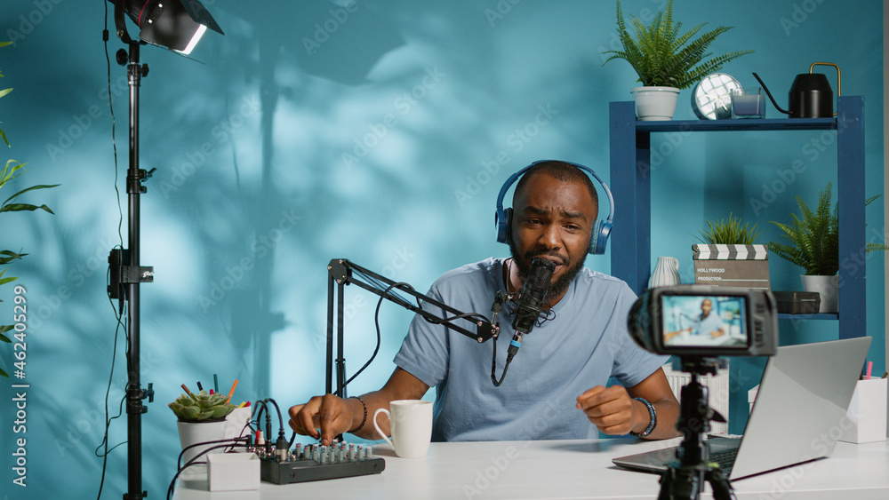 Poster blogger filming video with camera for podcast channel while using recording equipment and laptop for