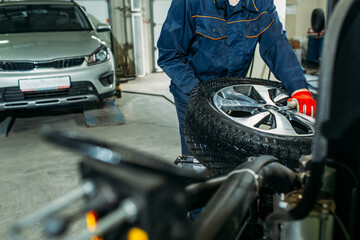 car service, tire fitting, an employee performs washing and wheel balancing on special installations