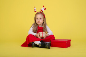 Portrait of happy little  girl Christmas  holding present box and looking at camera on yellow background