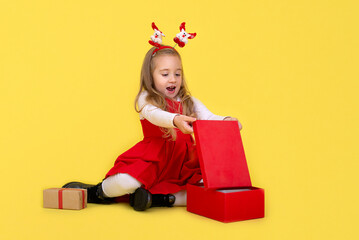 Portrait of happy little  girl Christmas  holding present box and looking at camera on yellow background