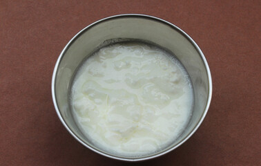 Curd in a steel bowl isolated on brown background