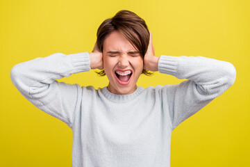 Photo of annoyed troubled lady hands cover ears scream wear blue pullover isolated yellow color...