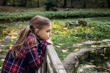 Portrait of a lovely little girl enjoys the beauty of an autumn in the park. Autumn mood..