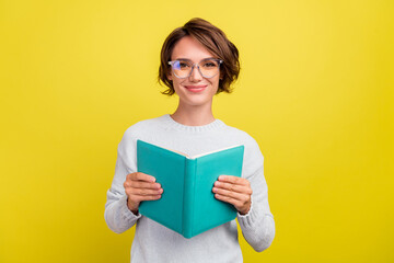 Photo of cheerful student lady read book novel wear eyewear blue pullover isolated yellow color background