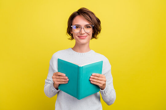 Photo of cheerful student lady read book novel wear eyewear blue pullover isolated yellow color background