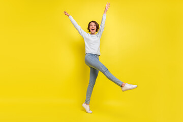 Fototapeta na wymiar Photo of funny positive lady raise hands dance wear blue sweater jeans sneakers isolated yellow color background