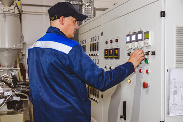 Hand pressing on green button of the machine in the factory