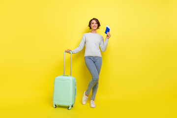 Photo of positive tourist lady hold tickets bag wear blue sweater jeans footwear isolated yellow...