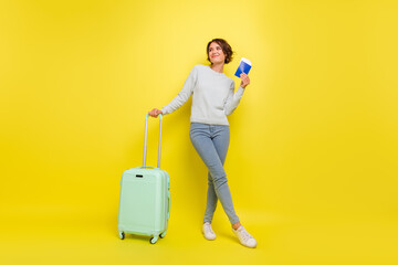 Photo of dreamy lady hold passport case look empty space wear blue sweater jeans shoes isolated yellow color background