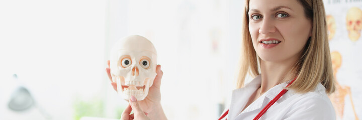Female doctor teacher holding human skull closeup