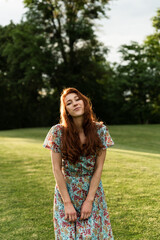 a red-haired girl with freckles on her face runs and smiles cutely at sunset. portrait of a beautiful girl of extraordinary appearance. unique appearance of a European red-haired girl. walk 