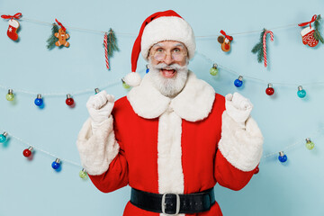 Old bearded Santa Claus man 50s wears Christmas hat red suit clothes posing do winner gesture isolated on plain blue background studio. Happy New Year 2022 celebration merry ho x-mas holiday concept.
