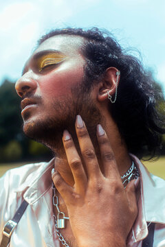 dreamy portrait of a dark skinned Indian man in Malaysia, with make up, in a field, surrounded by nature
