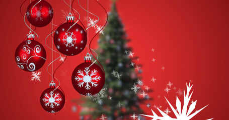 Image of snow falling and baubles over christmas tree on red background