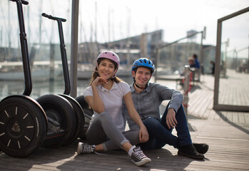 young couple guy and girl are walking on the segway along the board paved promenade in the port of...