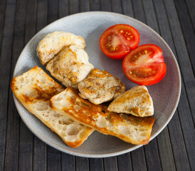 toasted pieces of chicken breast, toast and tomatoes on plate