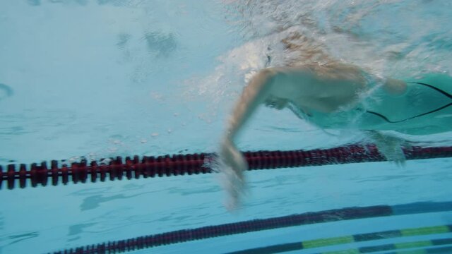 Underwater and upside-down shot of a Caucasian female sportswoman swimming in the freestyle, performing an open turn, and sliding through the water.