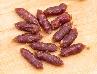 A bunch of oval mini sausages for beer on a wooden background, close-up. Beer snack