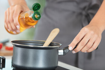 close-up of male hand pouring oil into pan