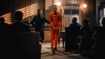 Cinematic Court of Law and Justice Trial Proceedings: Portrait of Accused Sad Male Criminal in Orange Jumpsuit Led Away by Security Guard in Front of Judge and Jury. Sentenced to Serve Jail Time. - obrazy, fototapety, plakaty