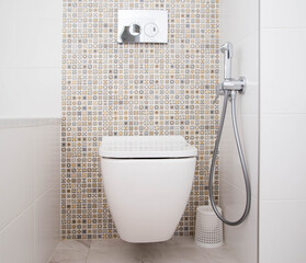 Modern wall-mounted toilet with shower for private spaces. White and clean bathroom