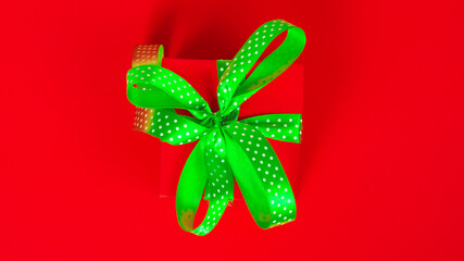 red gift box with green ribbon and bow on red background. Happy Christmas, New year, Birthday, Valentines day, Womens day