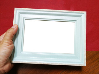 Hand holding a picture frame on red paper background