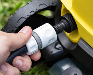Male hand puts the quick-release hose coupling for water on the pressure washer, close-up.