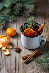 Traditional tasty mulled wine hot drink with mandarin apple spices and christmas tree in white cup