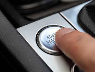 Man's finger presses modern car button to start car, macro.