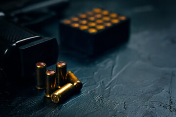 Black gun with cartridges on table. Automatic firearms with bullets. Weapons on concrete background. Pistol for defense or attack.