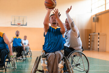Disabled War veterans mixed race and age basketball teams in wheelchairs playing a training match in a sports gym hall. Handicapped people rehabilitation and inclusion concept