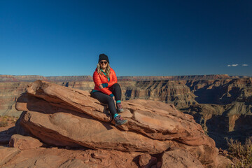 Smiling girl sitting on rock overlooking the Grand Canyon, Arizona, USA