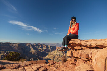 Smiling girl sitting on rock overlooking the Grand Canyon, Arizona, USA
