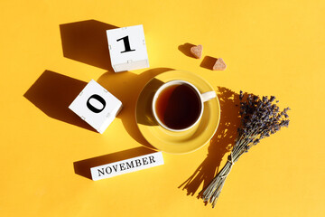 Calendar for November 1: cubes with numbers 0 and 1, the name of the month in English, a cup of tea, two pieces of sugar in the shape of a heart, a bouquet of lavender, shadows from objects