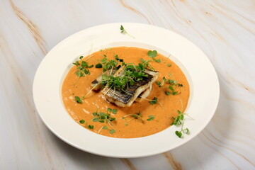 fried sea bass fillet on a vegetable sauce decorated with sprouts. Fried sea fish 