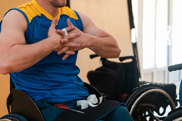 a disabled basketball player puts on a corset and bandages on his arms and fingers in preparation for a game in the arena