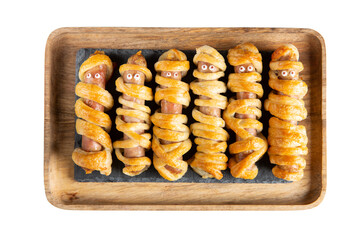 Halloween mummy hot dogs. Sausages with eyes wrapped in dough in wooden tray isolated on white...