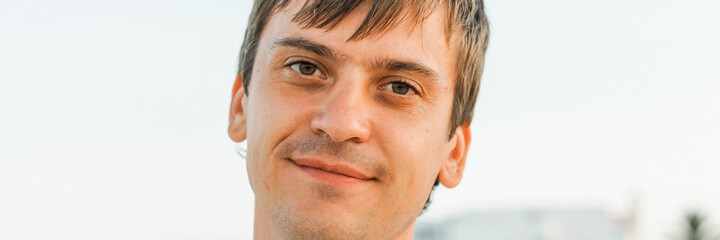 portrait of the face of a thirty year old adult candid caucasian happy man or a guy solo traveling on a summer vacation. banner