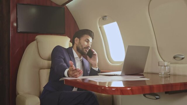 Businessman talking on the phone in the private jet.