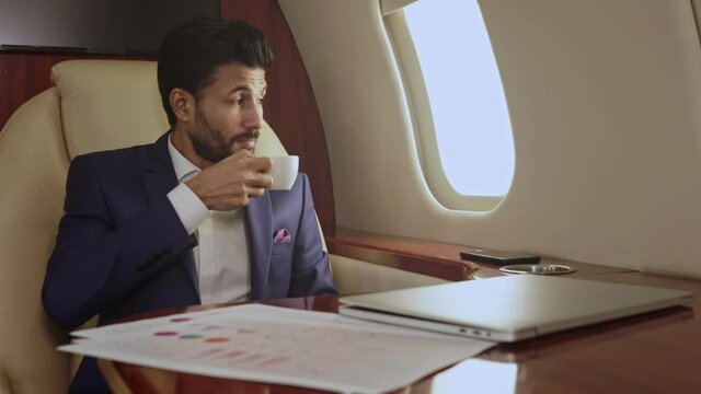 Businessman drinking coffee in the private jet.