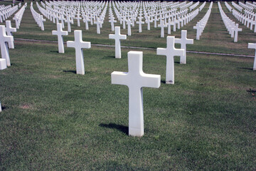 expanse of solemn crosses in a green field of the memorial cemetery of American soldiers who died...