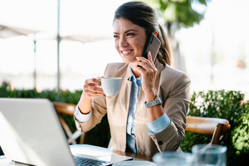 Businesswoman working in cafe. Beautiful woman with lap top talking to the phone.