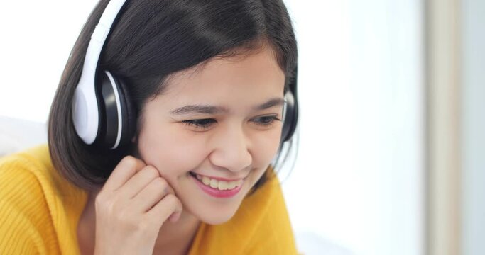 Portrait of smiling young Asian women is resting listening to music on bed with earphone. Close up face of Asia girl watching on video for entertainment at home