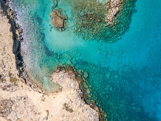 Aerial view from flying drone on clear blue water of bay in Cyprus