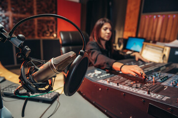 Young woman music producer working on a mixing soundboard while in her studio