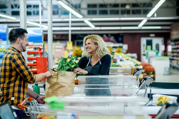Beautiful young cashier is smiling while working at the supermarket