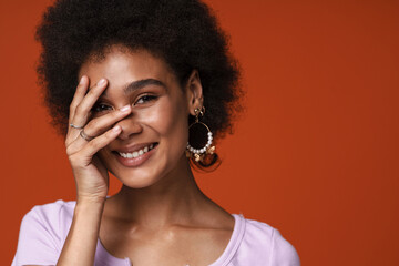 Young black woman wearing earrings smiling and covering her face